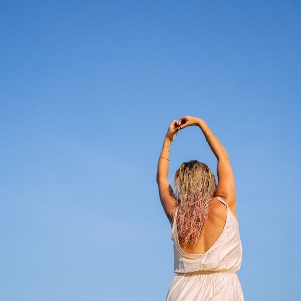 Person stretching joyfully in a bright, sunlit room.