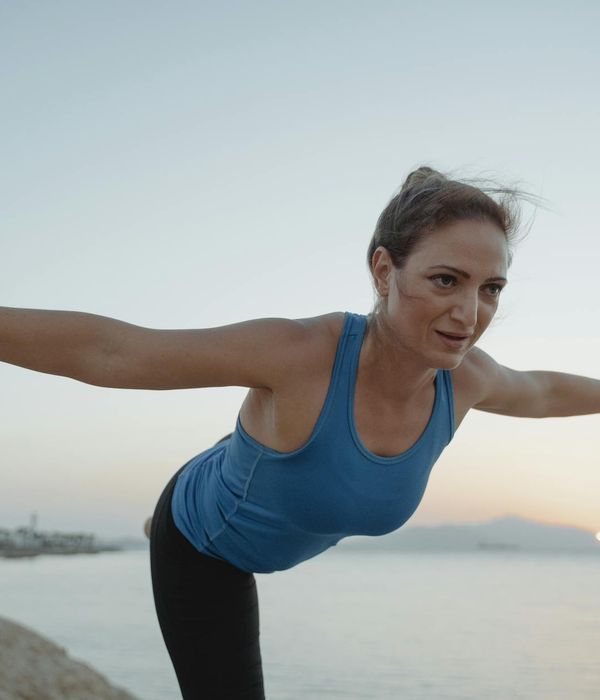 Woman in a peaceful yoga pose against a rising sun.